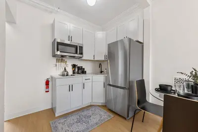 a kitchen with white cabinets and a stainless steel refrigerator at 3BR Harlem Stay with Washer with Dryer in New York