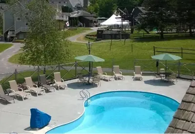 a swimming pool with chairs and umbrellas at 2 BR JIMINY PEAK w Mountain Views SLEEPS 7 Gorgeous in Hancock