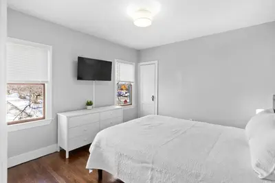 a white bedroom with a bed and a flat screen tv at Owl's Nest - 5BR apartment in New Haven