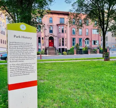 a park history sign in front of a pink building at Historic Studio Near Trinity College with Fast WiFi in Hartford