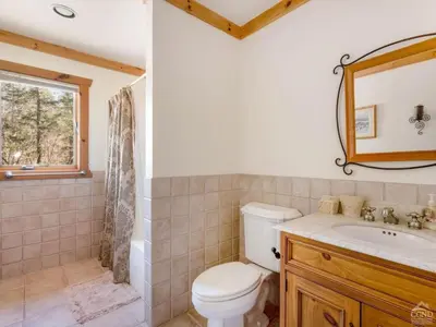 a bathroom with a toilet and a sink and a mirror at Fireplaces, Home Theater, Ski-In Out Windham Lodge in Windham