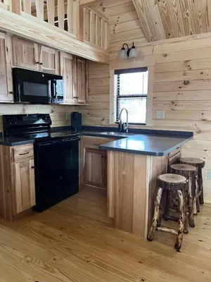 a kitchen with a black island in a log cabin at Tiny Cabin #5 by Windham NY Escape 'Scenic Stay' in Hensonville
