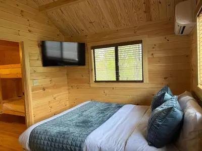 a bedroom with a bed and a flat screen tv at Tiny Cabin #5 by Windham NY Escape 'Scenic Stay' in Hensonville