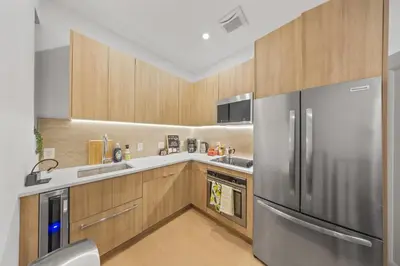 a kitchen with a stainless steel refrigerator and wooden cabinets at Double Room at a shared Apartment near Times Square in New York