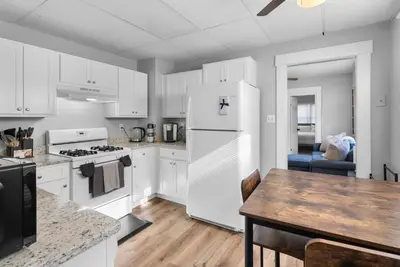 a kitchen with white cabinets and a table and a refrigerator at Quiet & Cozy Room by SCSU in New Haven