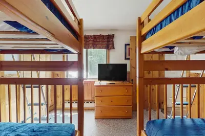 a bedroom with two bunk beds and a tv at Ski Haus Retreat - Unit A in Dover