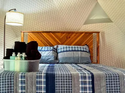 a bedroom with a bed with a blue and white checked blanket at Peaceful Dome Getaway in the Catskills in Gilboa