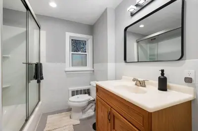 a bathroom with a sink and a toilet and a mirror at Spacious 3BR Apt Near MetroNorth in Yonkers