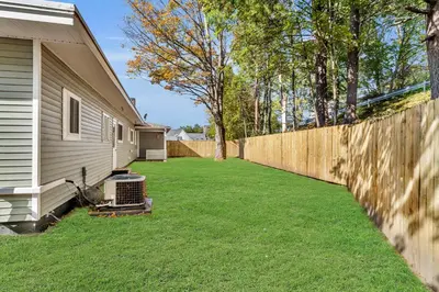 a fence next to a house with a yard at The Main Lineup 3 - All Star Baseball Rentals in Oneonta