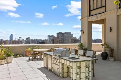 an outdoor kitchen on a patio with a view of the city at Freeman 603 by Rove Travel - Studio with Shared Amenities in New York