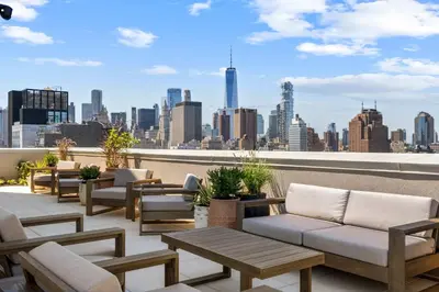 a rooftop patio with couches and a view of the city at Freeman II by Rove 1BR Condo with Shared Amenities in New York