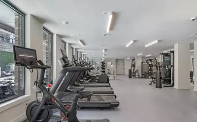 a gym with rows of treadmills and a row of exercise bikes at Blueground Williamsburg rooftop nr McCarren Park NYC-2076 in Brooklyn