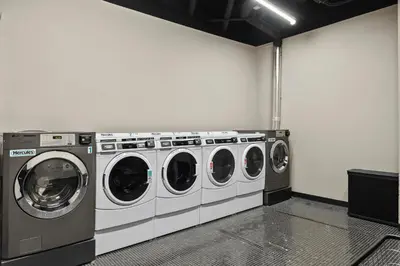 a laundry room with three washing machines in it at Freeman 303 by Rove Travel - 1BR Condo with Shared Amenities in New York