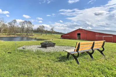 a bench sitting in the grass next to a red barn at Country Escape Close to Ski Resort in Pleasant Mount