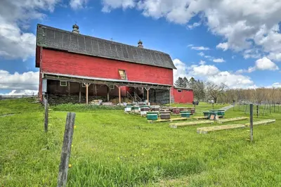 a red barn in a field with a fence at Deluxe Duplex close to Ski Runs in Pleasant Mount
