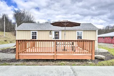 a house with an umbrella on a wooden deck at Countryside Retreat Close to Ski Slopes in Pleasant Mount