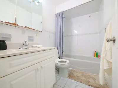 a white bathroom with a toilet and a tub and a sink at Cozy Private Room with Shared Kitchen near NYC in Jersey City