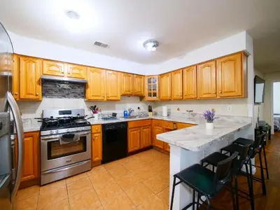 a kitchen with wooden cabinets and a stove top oven at Mins to NYC Comfy Private Room in Shared Home in Jersey City