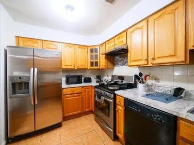 a kitchen with wooden cabinets and a stainless steel refrigerator at Charming Room with Shared Space close to NYC in Jersey City