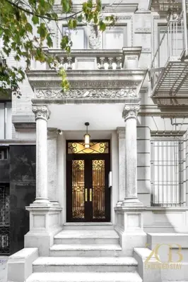 a white house with a black door and stairs at Spacious 1-Bedroom Retreat Near Central Park in New York