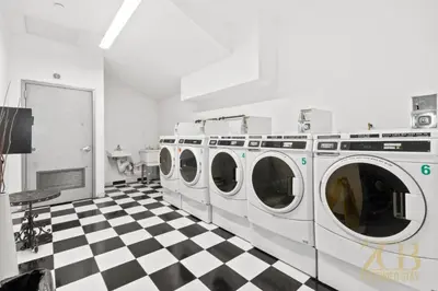 a laundry room with four washing machines on a checkered floor at Fabulous 1 Bedroom in the Heart of Manhattan in New York
