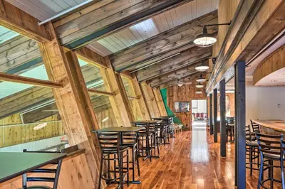a row of tables and chairs in a room with wooden walls at 8 Mi to Mt Snow Cozy Bear Cabin with Hot Tub! in Wilmington
