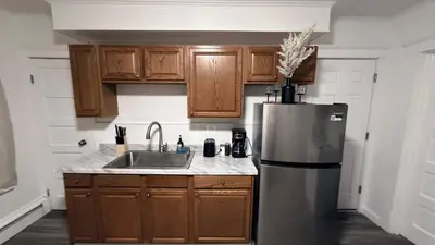 a kitchen with wooden cabinets and a stainless steel refrigerator at Nona - Private Room 1 with Parking, Desk & Fast WiFi near Yale, Quinnipiac, SCSU & Hospitals in Hamden