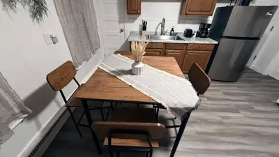 a kitchen with a wooden table with chairs and a refrigerator at Nona - Private Room 3 with Parking, Desk & Fast WiFi near Yale, Quinnipiac, SCSU & Hospitals in Hamden
