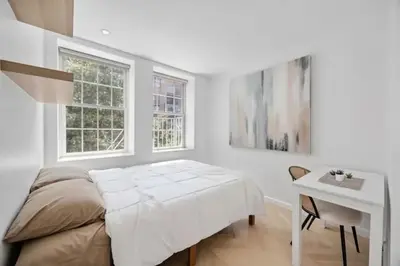 a bedroom with a bed and a desk and two windows at Fully renovated 3 BDR Apt East Village in New York