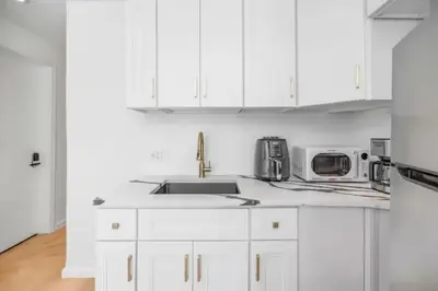 a white kitchen with white cabinets and a sink at Bright Luxury 3-Bedroom Apartment in East Village in New York
