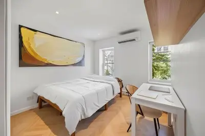 a bedroom with a bed and a table and a painting at Bright Luxury 3-Bedroom Apartment in East Village in New York