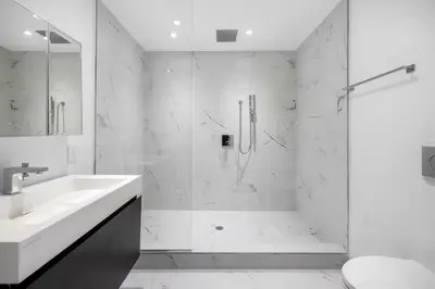 a white bathroom with a shower and a sink at Bright Luxury 3-Bedroom Apartment in East Village in New York