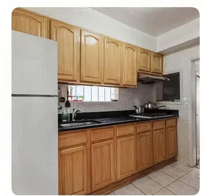 a kitchen with wooden cabinets and a white refrigerator at \u7ebd\u7ea6\u53d1\u62c9\u76db\u5e72\u51c0\u6574\u6d01\u5b89\u5168\u5c0f\u5355\u95f4 in Flushing