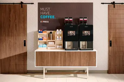 a coffee shop with a counter with a coffee maker on it at Holiday Inn Express & Suites East Greenbush Albany-Skyline by IHG in Rensselaer