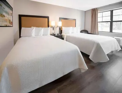a hotel room with two beds with white sheets at Extended Stay America Suites - White Plains - Elmsford in Elmsford
