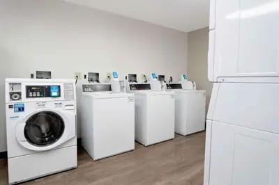 a laundry room with four washing machines and a refrigerator at Extended Stay America Suites - White Plains - Elmsford in Elmsford
