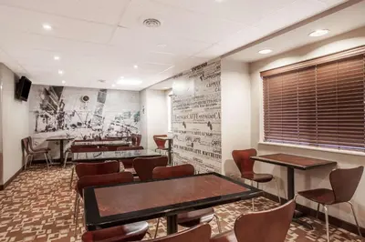 a waiting room with tables and chairs and a wall at Super 8 by Wyndham Schenectady/Albany Area in Schenectady