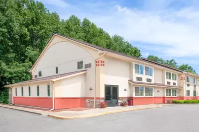 a large white building with a red garage at Super 8 by Wyndham Oneonta/Cooperstown in Oneonta