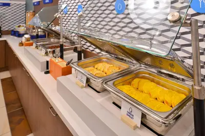 a buffet line with trays of food on display at Holiday Inn Express & Suites Utica by IHG in Utica