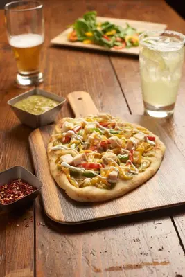 a pizza sitting on top of a wooden table at Hyatt Place Garden City in Garden City