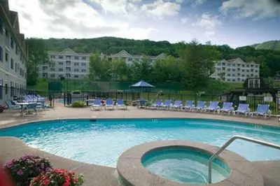 a large swimming pool with chairs and a building at Deluxe Ski On Off 1BR Suite Sleeps 4 on Jiminy Mtn in Hancock