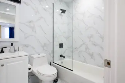 a white bathroom with a shower and a toilet at 240-15 Luxury Studio Prime Location W&D in New York