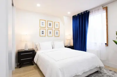 a bedroom with a white bed and blue curtains at 75-5A Luxury 3BR Duplex W D in unit Elevator in New York